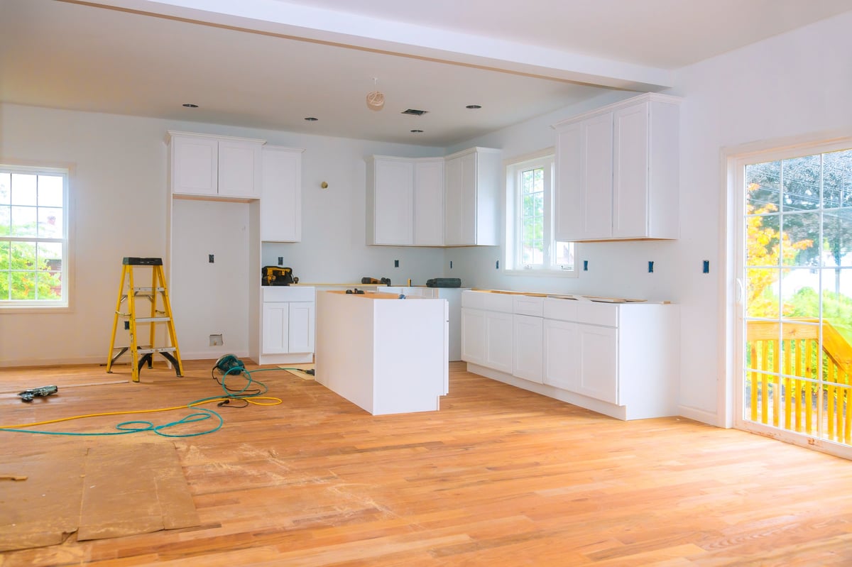 Bright kitchen with new white cabinets and hardwood flooring under renovation